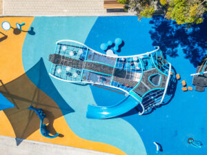 A modern play structure with a smooth Alpine slide and blue surfacing.