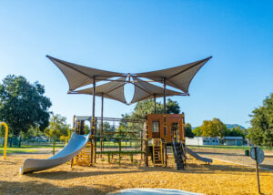 Playground equipment with large shade structure over the top.